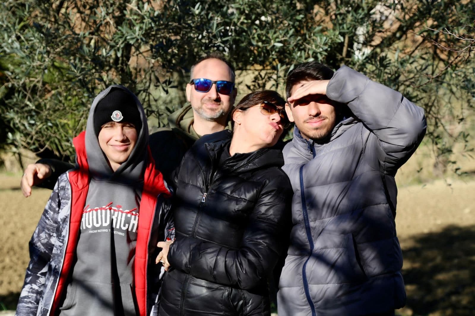 Sara con il marito e i due figli, ormai grandi, sotto un olivo